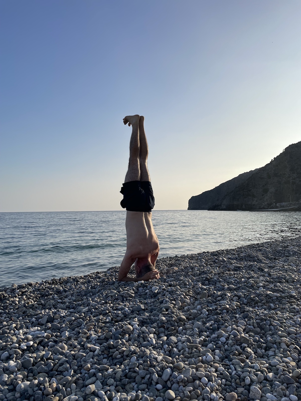 Greg stands on his head on the beach
